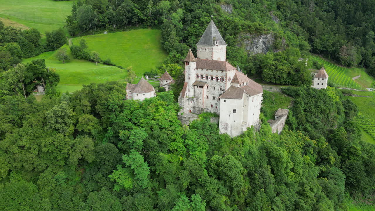 Trostburg Castle, a medieval fortress nestled in the Italian Dolomites, seen from above, surrounded by lush greenery