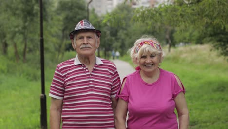 una pareja caucásica anciana caminando en el parque abrazándose. un hombre anciano camina con una mujer. marido, esposa