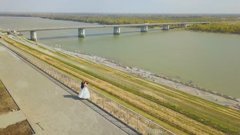 just married couple on hilly embankment near river aerial