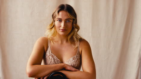 studio shot of confident natural woman in underwear promoting body positivity sitting on chair