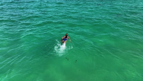 Vista-Aérea-De-Una-Niña-Nadando-Y-Buceando-En-Aguas-Turquesas-Del-Caribe