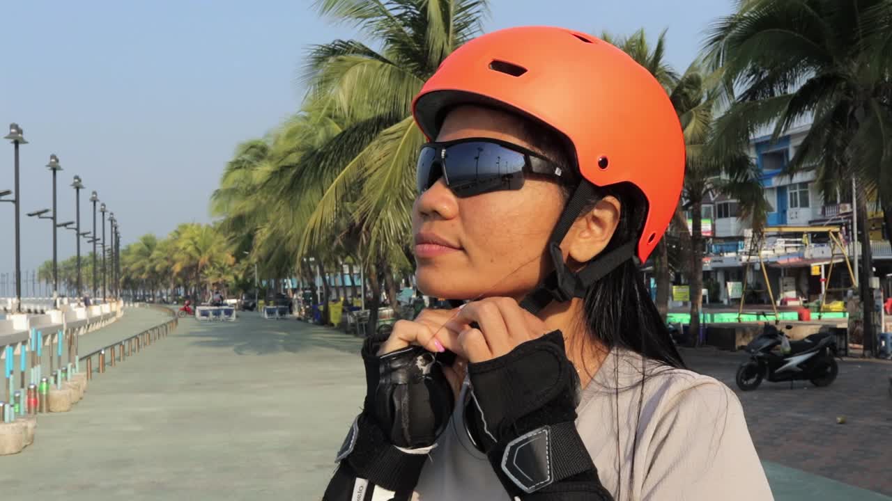una patinadora en línea se pone un casco protector y se prepara para patinar en el parque de tailandia