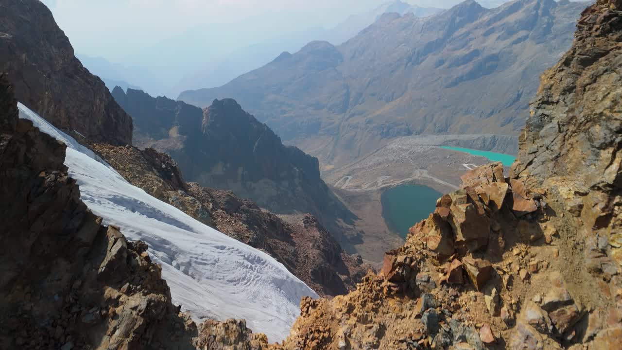 Aerial shot rises over a rugged ridge to reveal a dramatic glacier valley and turquoise lakes near Montaña Mateo in the Peruvian Andes
