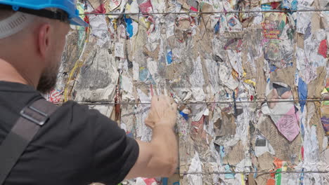 el gerente de la instalación de reciclaje de papel reciclado comprueba la calidad de las balas de papel