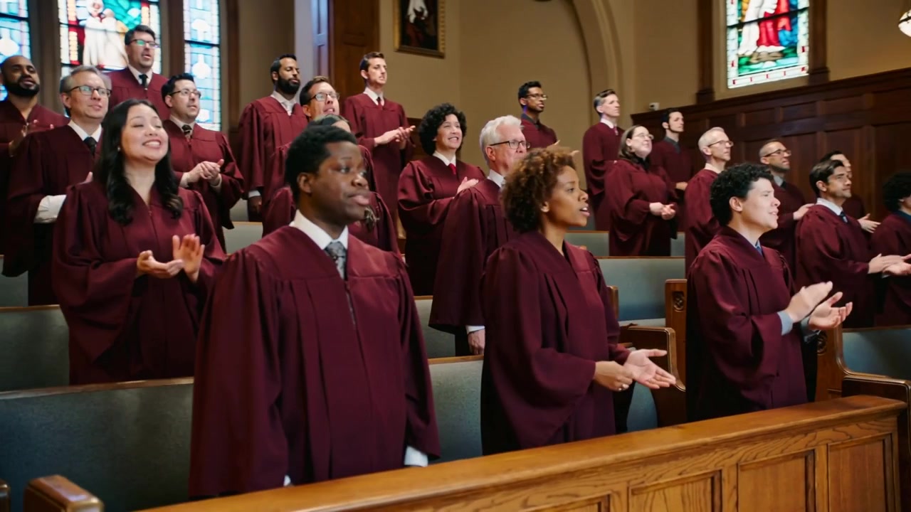 Singing choir responding to hymn starting in church, clapping, wearing maroon robes for worship
