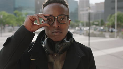 close up portrait of trendy african american man student intern puts on glasses smiling happy at camera enjoying college lifestyle