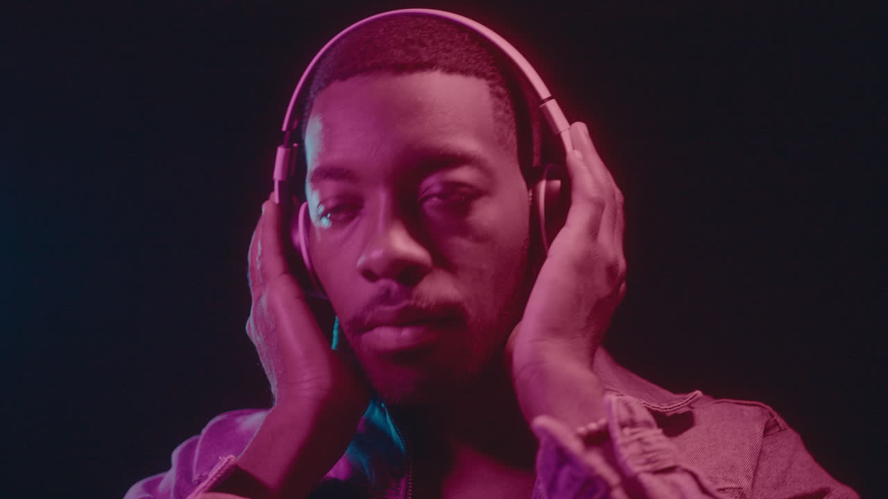 African American Guy in Headphones Dancing in Neon Light
