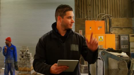 trabajador que usa una tableta digital en un taller de fundición 4k