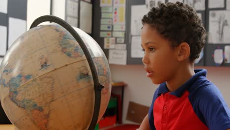 Seitenansicht-Eines-Afroamerikanischen-Schuljungen,-Der-Am-Schreibtisch-Im-Klassenzimmer-Der-Schule-Den-Globus-Studiert,-4k
