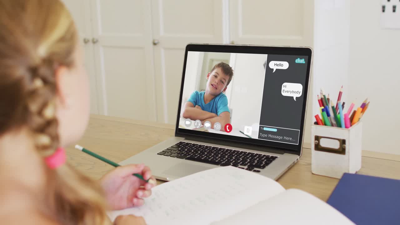 Schoolgirl using laptop for online lesson at home, with her colleague and web chat on screen