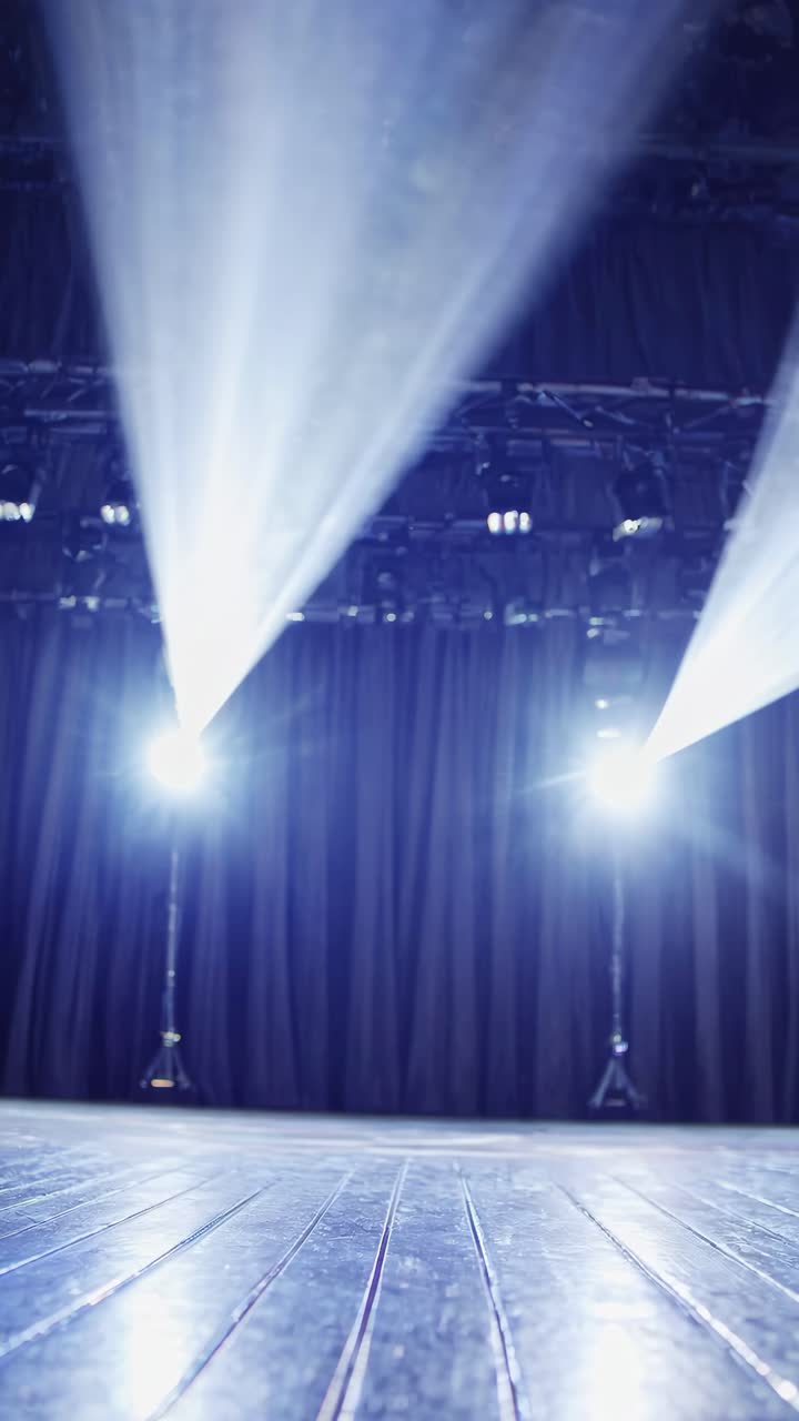 Low-angle shot of a dimly lit stage with spotlights and curtains, creating a dramatic video backdrop