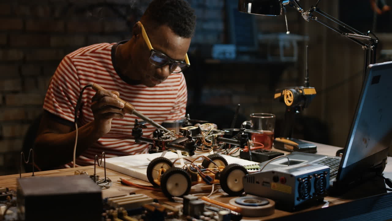 Man repairing a drone and rc car in a workshop