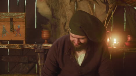 a man in medieval clothing stands in a dimly lit room with candles