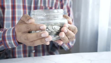 person holding a glass jar filled with coins