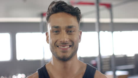 young biracial trainer with short dark hair and beard smiling at gym