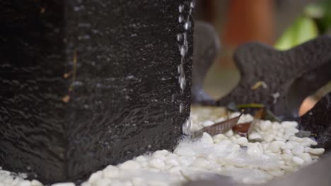 ornamental small stone water fountain trickling water, closeup pan slow motion