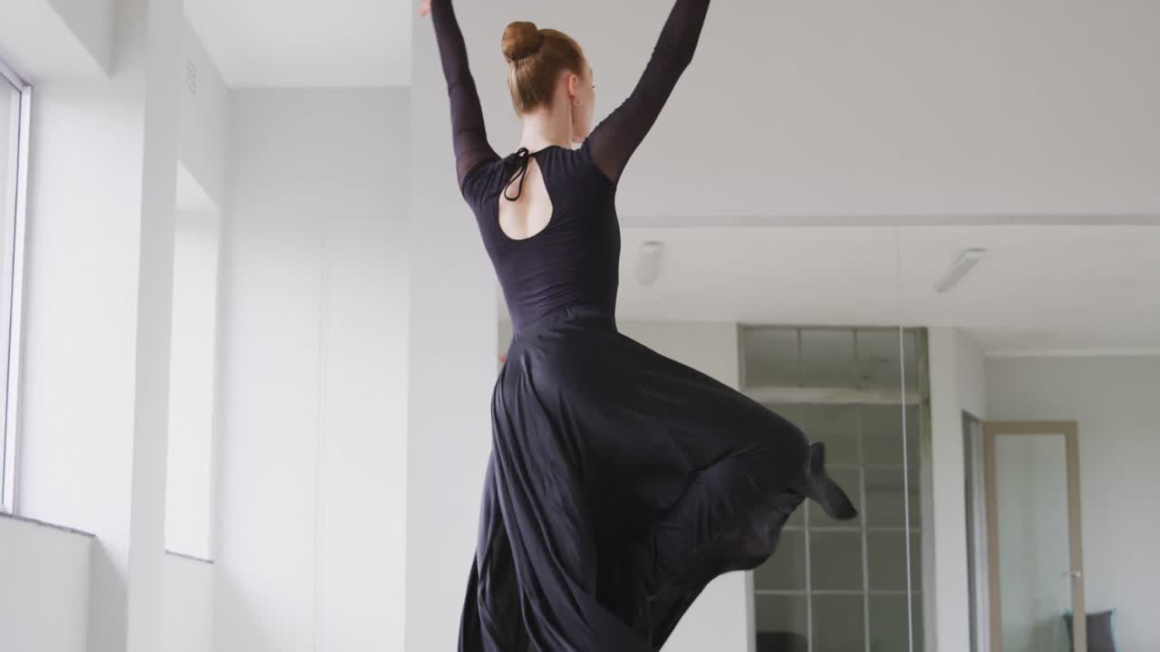 Caucasian female ballet dancer practicing ballet during a dance class in a bright studio
