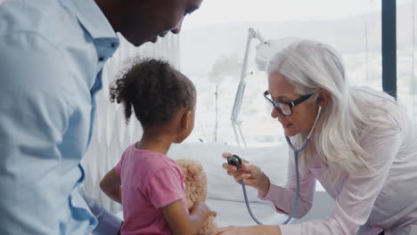 female doctor giving girl and her teddy bear medical exam on family consultation in office