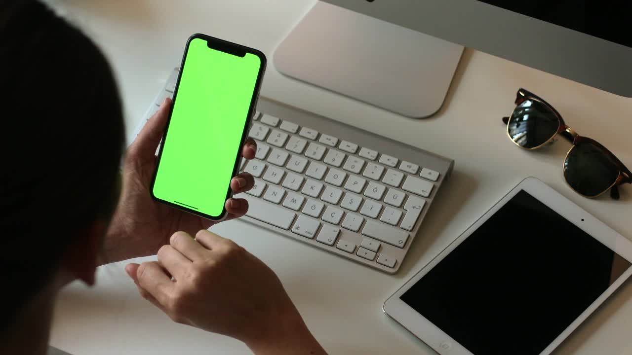 persona que sostiene un teléfono móvil con pantalla verde en la mano