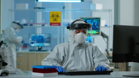 Scientist-in-coverall-examining-blood-test-tubes-at-laboratory-DNA-testing-analysis