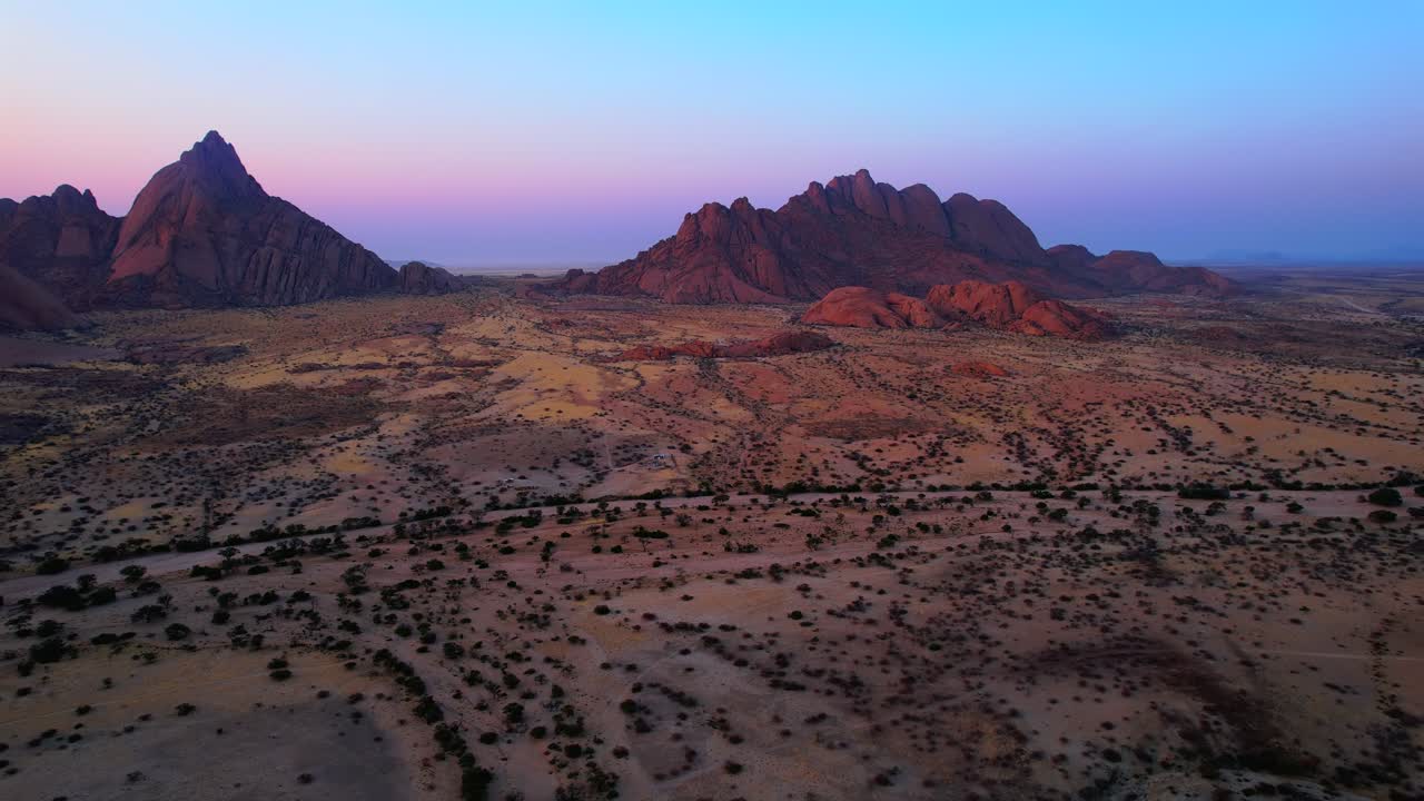 Rugged granite peaks over arid desert plain at sunset in Spitzkoppe, Namib Desert, Namibia