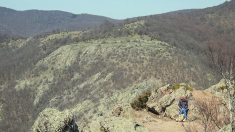 Frau-Wanderer-Sitzt-Auf-Steinen-Und-Bewundert-Die-Aussicht-Auf-Den-Wanderweg,-Jib-Shot-Hand-Gehalten