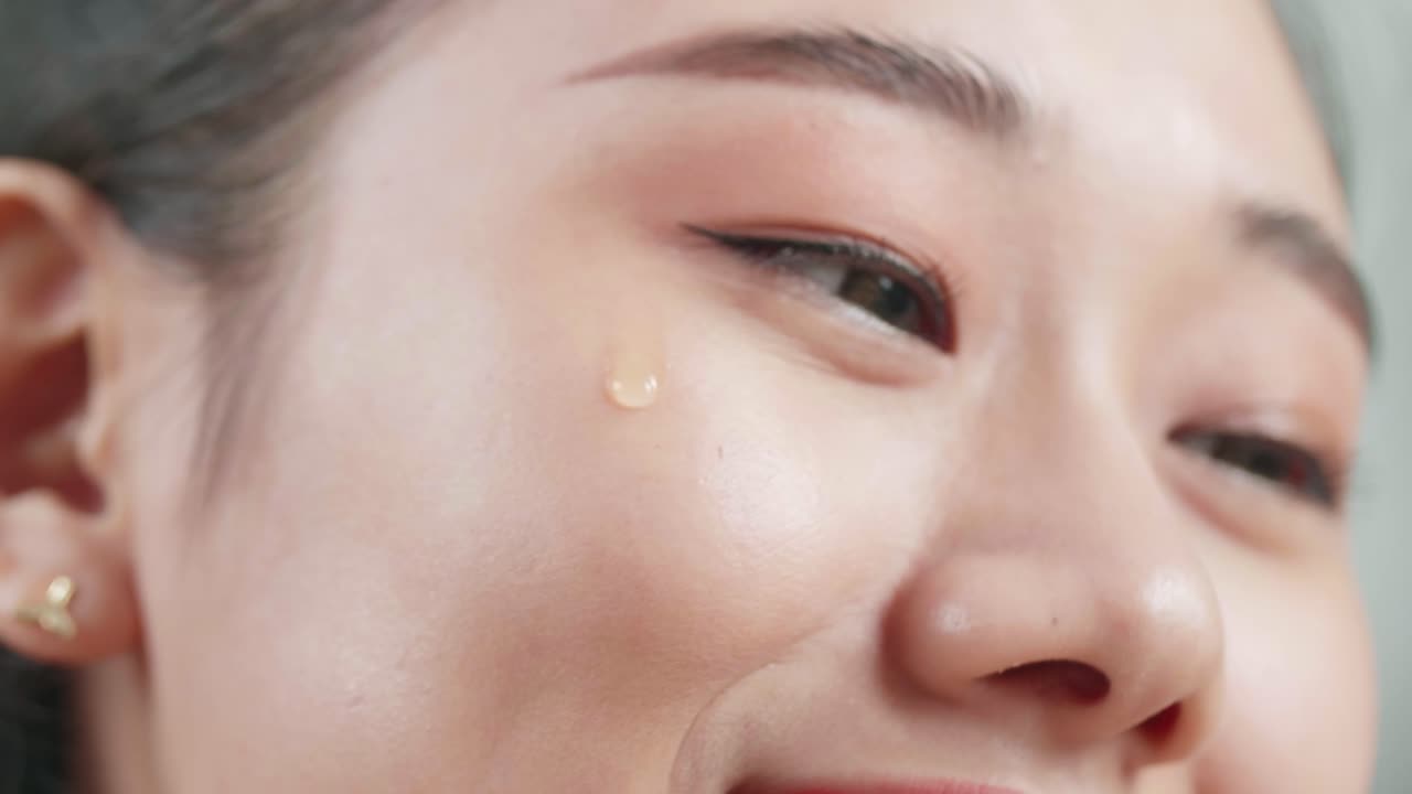 아름다운 젊은 아시아 여성이 집에서 메이크업하는 동안 혈청을 적용하고 미소 짓는 클로즈업