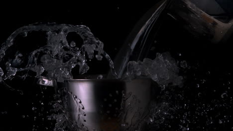 water pouring over colander on black background