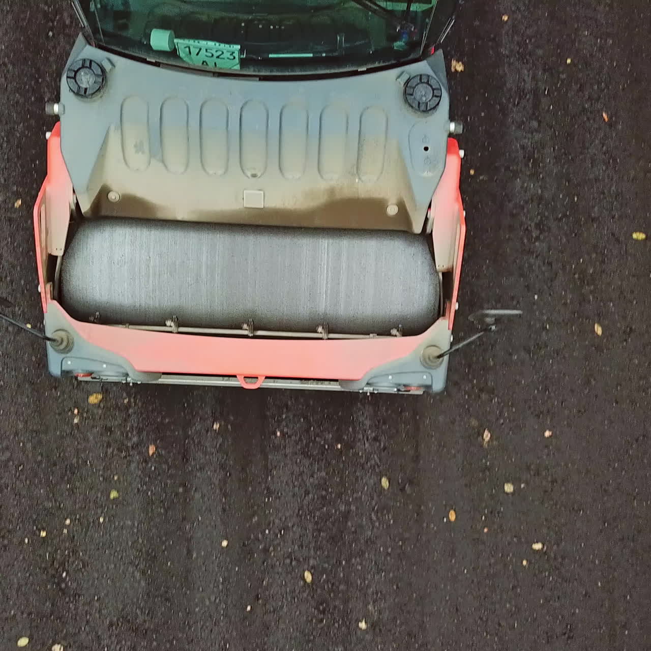 Close-up of roller machine pressing new asphalt. Top view of a spinning wheel of a steamroller while laying black asphalt. Drone view.