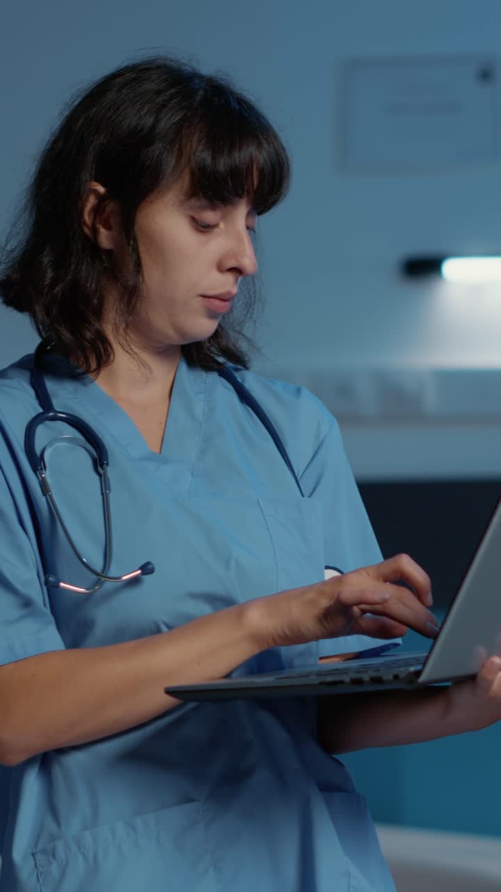 Vertical video: Practitioner nurse holding laptop computer analyzing patient illness report