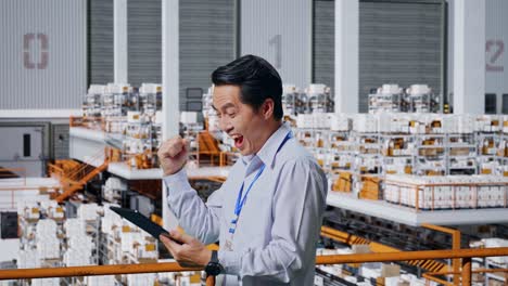 happy warehouse worker celebrating success with tablet