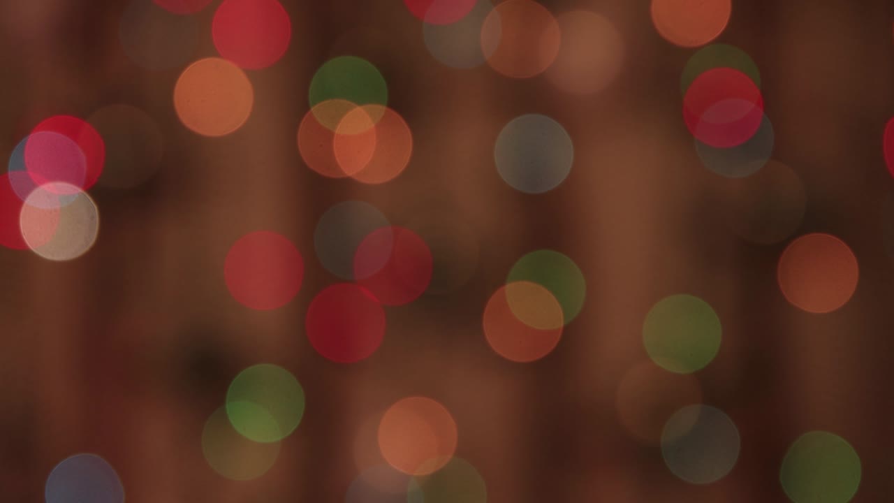 Festive delicate multicolored lights slowly swing in the dark and flicker.