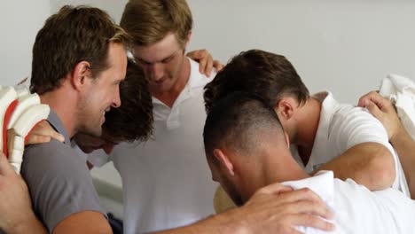 Cricket-team-forming-a-huddle-in-dressing-room