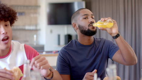 eating sandwiches and drinking juice, diverse friends enjoying casual hangout at home