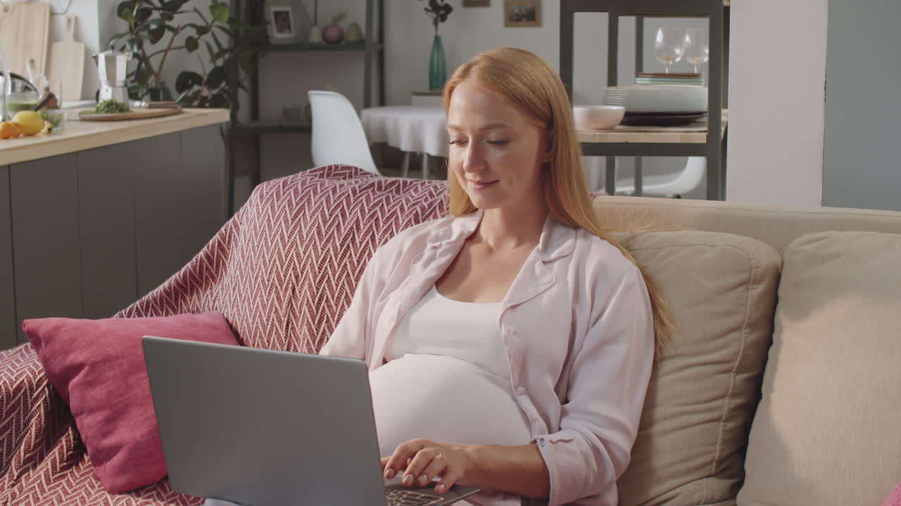 임신 한 여성 이 집 에서 노트북 을 사용 하고 있다