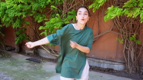 Woman dancing outdoors in front of trees