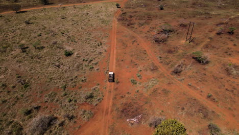 Un-Dron-Ariel-Disparó-Siguiendo-A-Un-Vehículo-De-Safari-A-Través-De-Un-Camino-De-Tierra-Seco-Y-árido-Africano-Mientras-Llevaba-A-Los-Viajeros-A-Buscar-Animales-Salvajes