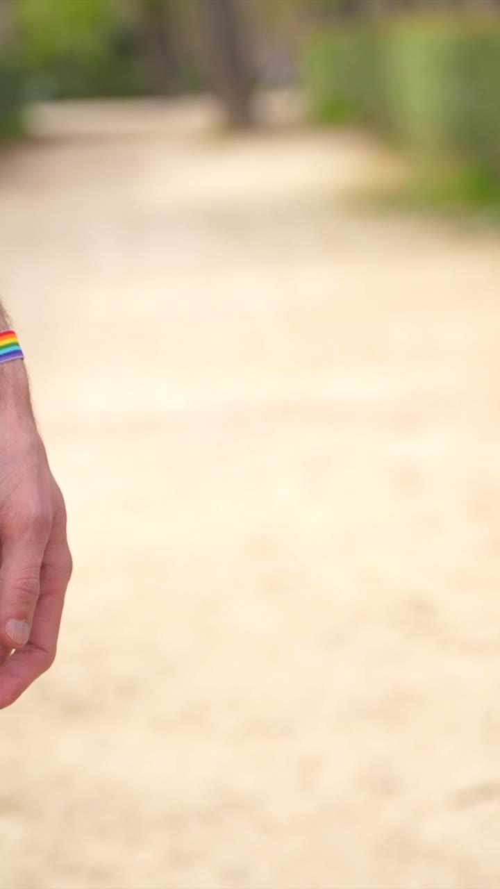 Mani che si tengono con braccialetti arcobaleno