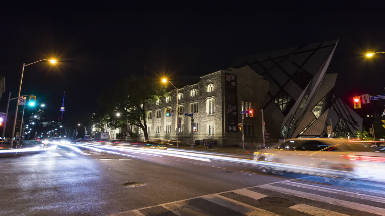 Timelapse del traffico notturno in un incrocio trafficato vicino al Royal Ontario Museum con l'iconica CN Tower illuminata in lontananza a Toronto