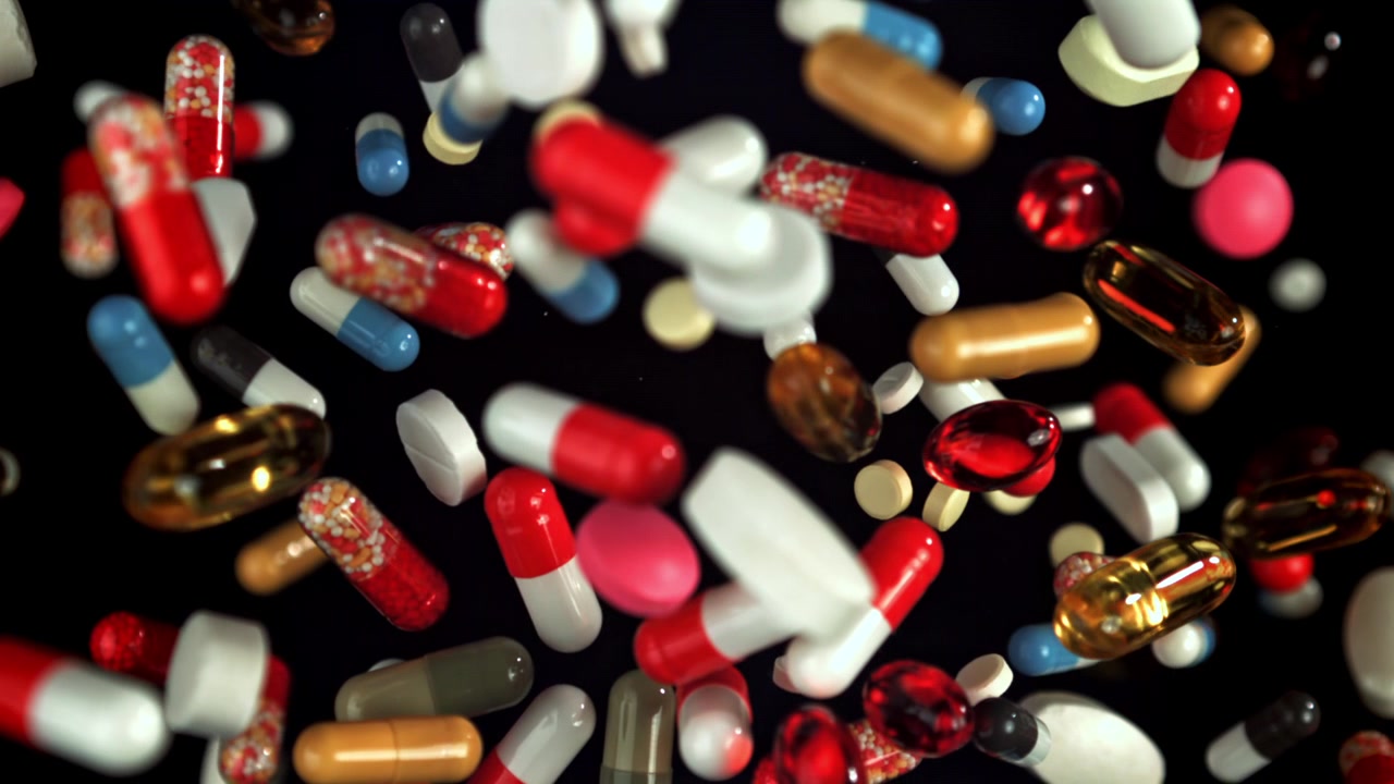 Colorful Pills and Capsules Falling in Slow Motion on Black Background