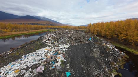 a large heap of household waste dominates the landscape, surrounded by golden autumn trees and serene mountains. this striking contrast highlights the environmental impact of waste disposal.