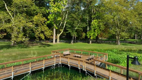 wooden boardwalk with benches over lush green wetland in a serene park setting