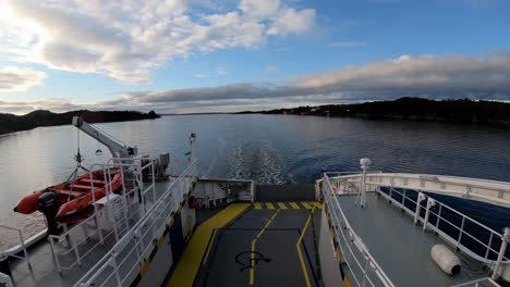 Looking-at-stern-of-zero-emission-car-ferry-passing-between-islands-and-slowing-down-for-port---Timelapse