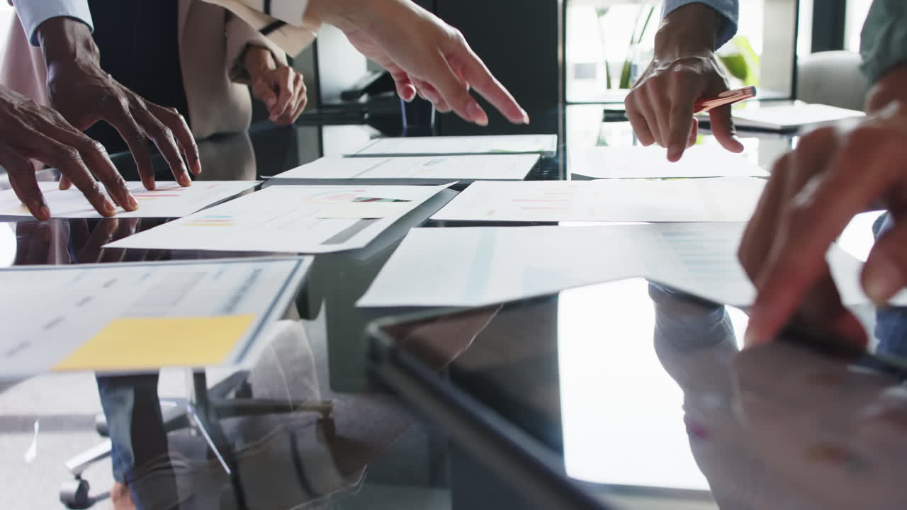Business team collaborating, pointing at documents and discussing project in office