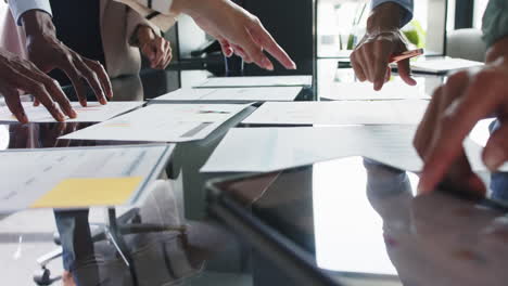 business team collaborating, pointing at documents and discussing project in office