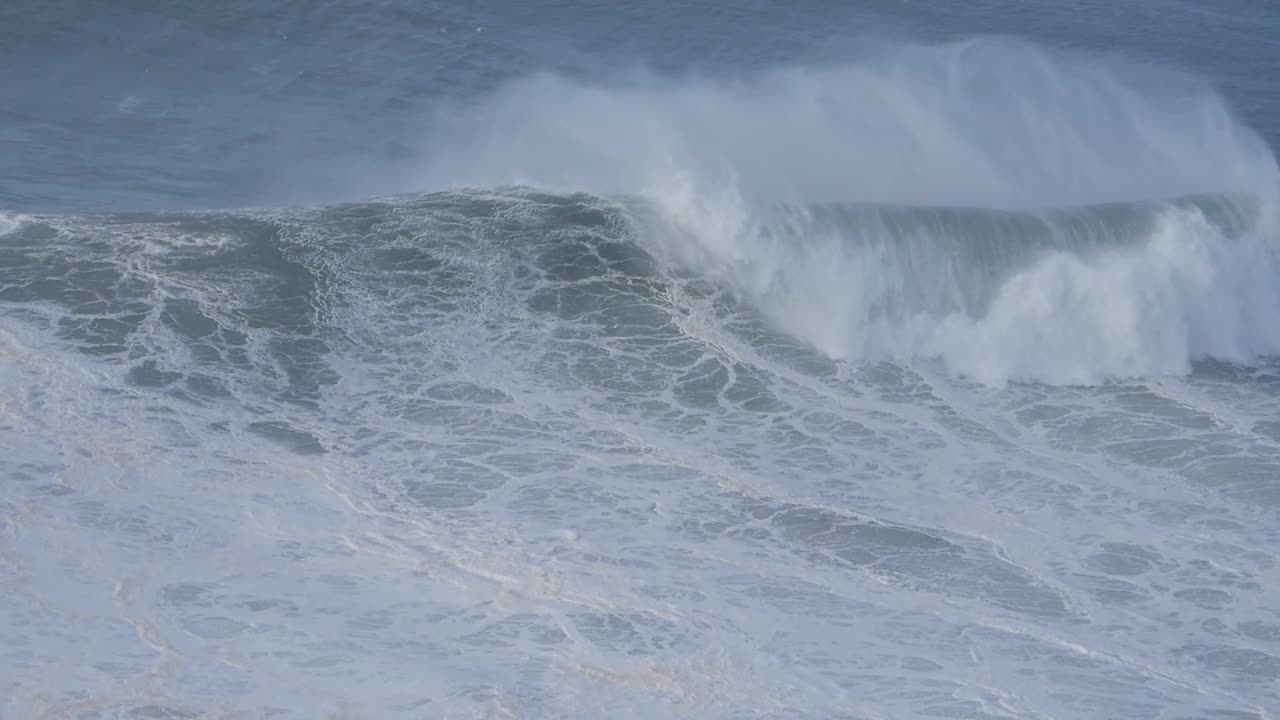 Enormous waves crashing on the coast of Nazare, Portugal, showcasing the raw power of the ocean