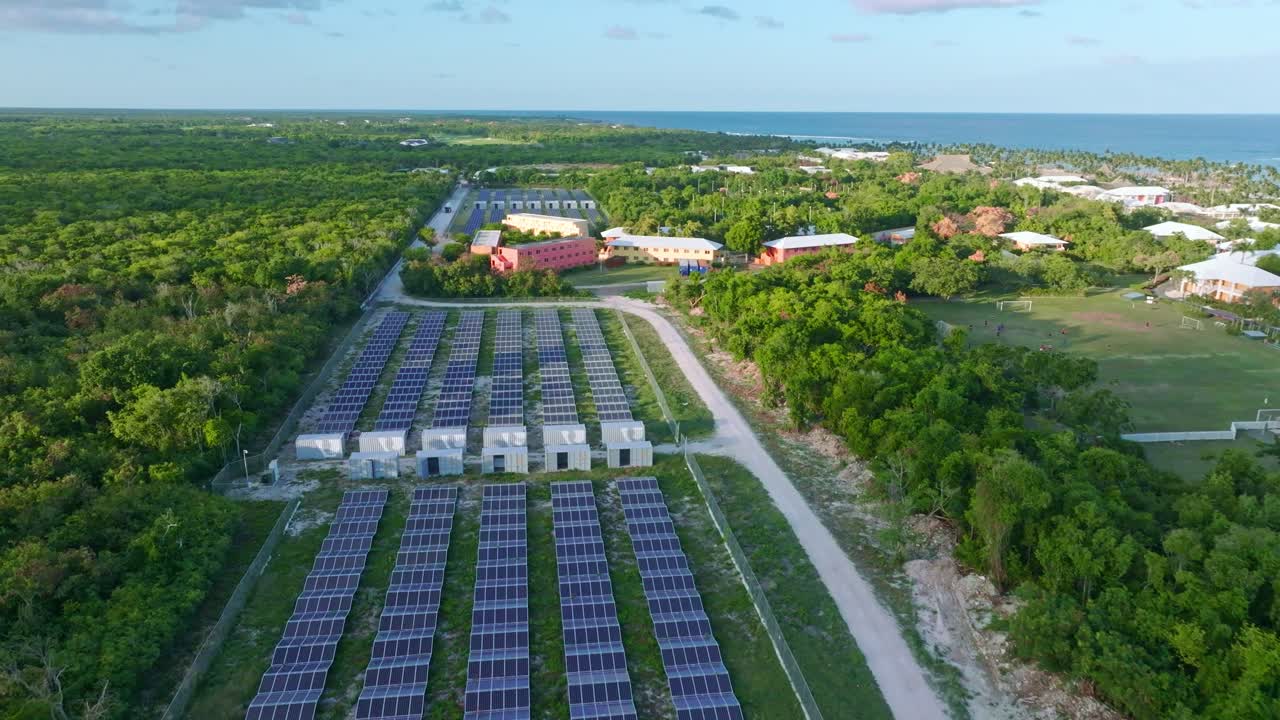 Aerial flyover large solar panel farm win tropical area of Dominican Republic in summer - Supply hotels with electricity - Renewable energy concept on island