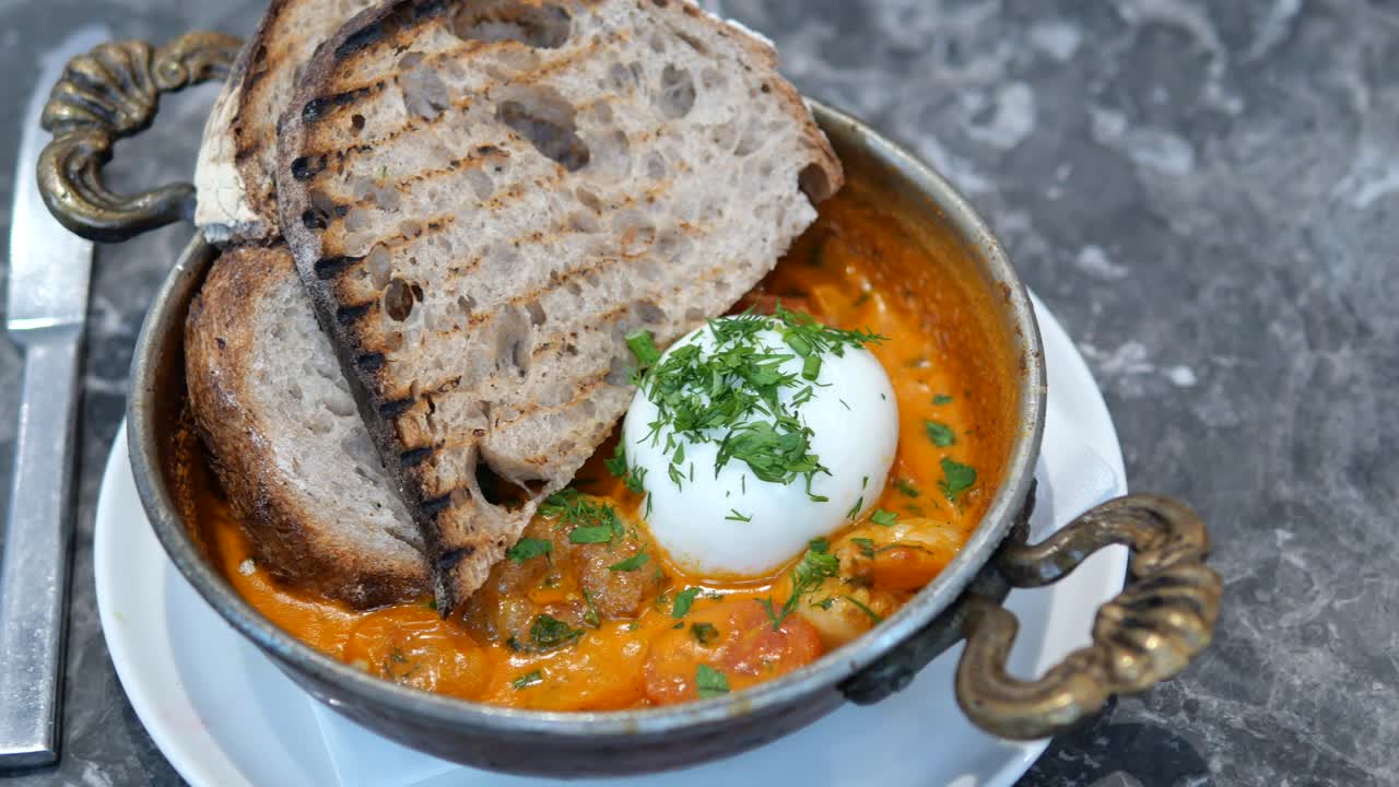 deliciosa shakshuka con huevo asado y pan tostado