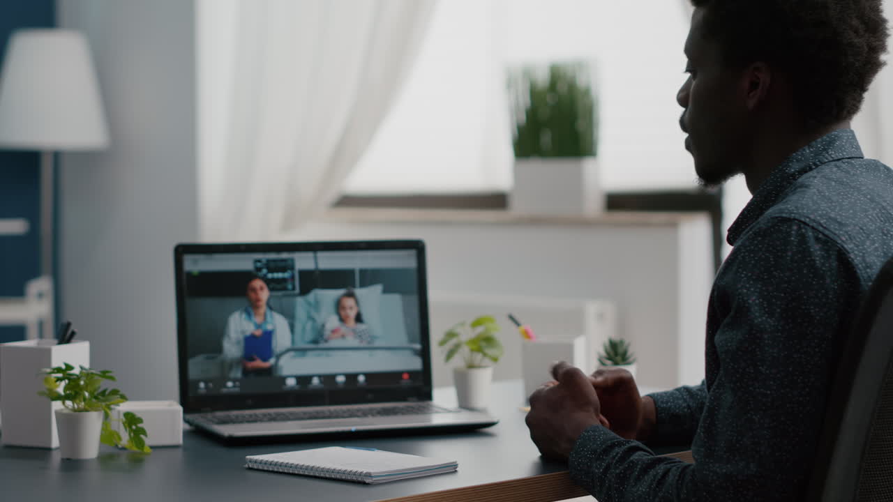 Selective focus on worried african american dad for her little girl in hospital ward, talking on video conference call