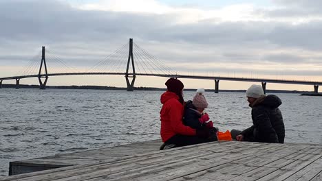 establishing shot of long suspension bridge and hiking family having picnic